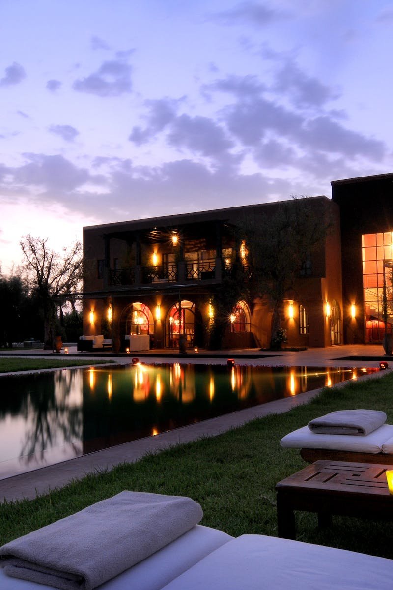 Elegant resort in Marrakech with a serene poolside view and illuminated architecture at dusk.