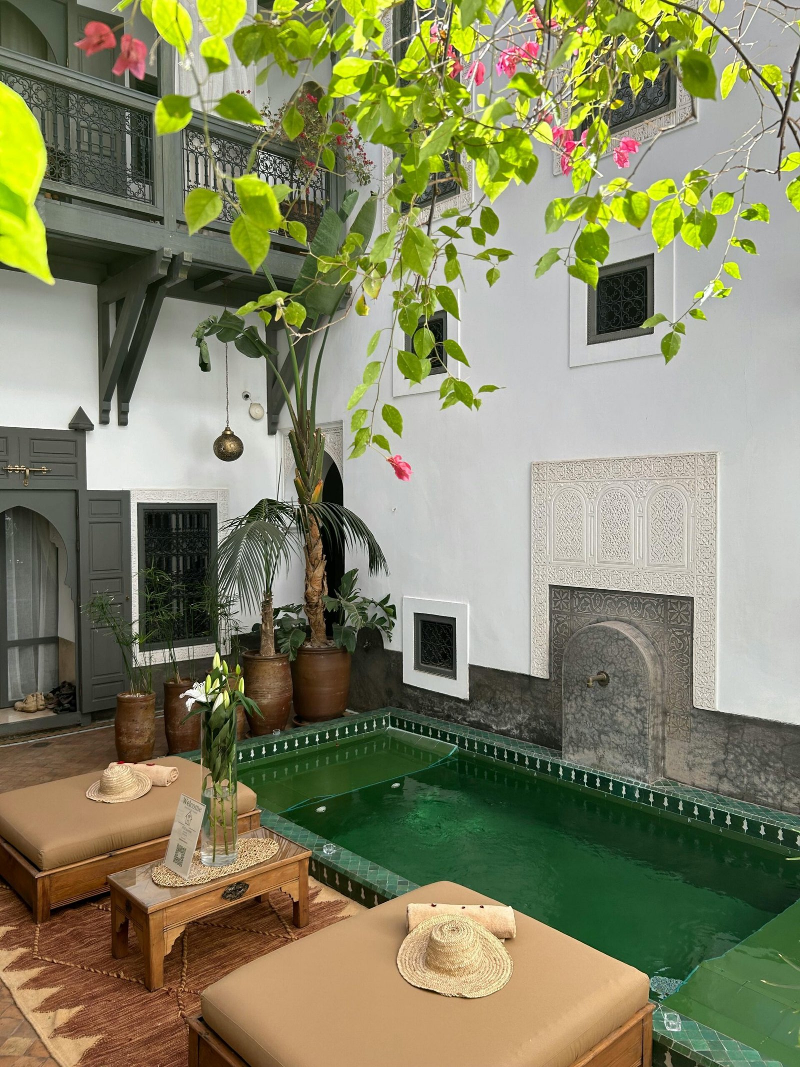 Charming Moroccan courtyard featuring a green pool, lush plants, and traditional architectural accents.